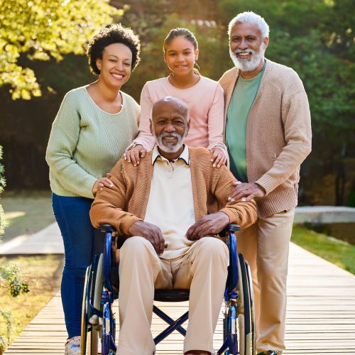 Senior care The image depicts a multi-generational family posing together in a warm, outdoor setting.